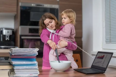 Multitasking mother is babysitting and working at home. Stock Photos