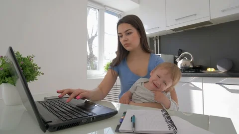 Multitasking mother with crying infant boy while working on laptop computer and Stock Footage 106178779