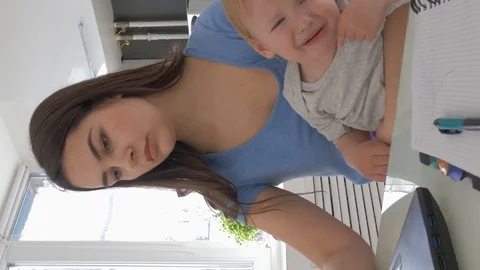Multitasking mother with crying infant boy while working on laptop computer and Stock Footage 125479093