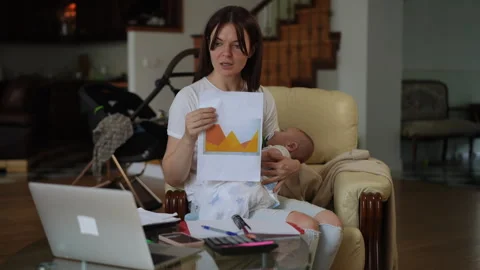 Multitasking mother working from home holding a baby during a video conference Video stock 331302849