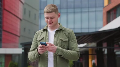 Multitasking outdoors Typing messages and shopping online on his smartphone Stock Footage 323925477