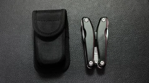 Multitool with a black case on a black leather background Stock Photos