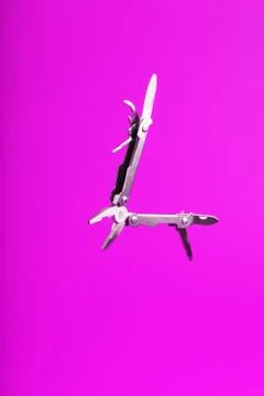 Multitool is a multi-functional tool on a pink background. The concept of an  库存照片