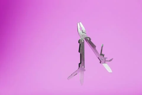 Multitool is a multi-functional tool on a pink background. The concept of an  写真素材