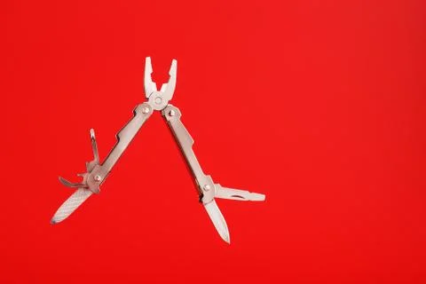 Multitool is a multi-functional tool on a red background. The concept of an o Foto stock