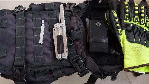 Multitool with opened serrated knife blade on black tactical backpack, top view Stock Footage 346248326