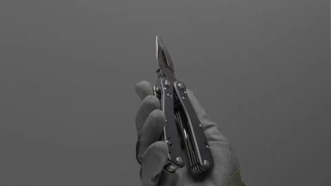 Multitool rotates in the hand on a gray background. Видео 266496350