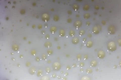 A multitude of small golden bubbles floating in a white liquid creating Stock Photos