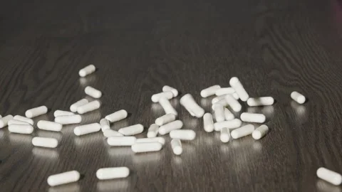 A multitude of white tablets are falling onto the table Stock Footage 270413959