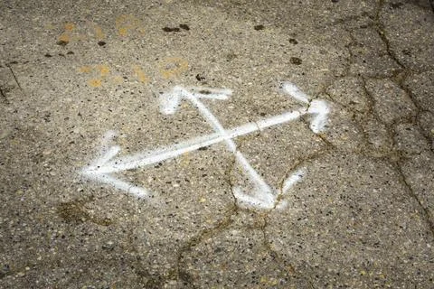 Multl-direction chalk arrows on pavement, cracks in the surface, potholes a.. Stock Photos