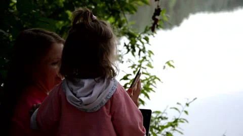 Mum and daughter sitting outside by the lake Stock Footage 131237237