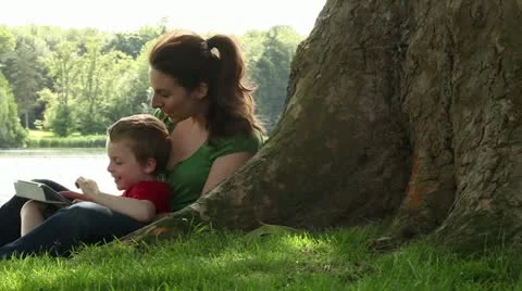 Mum and son playing on tablet by tree Stock Footage 18151301