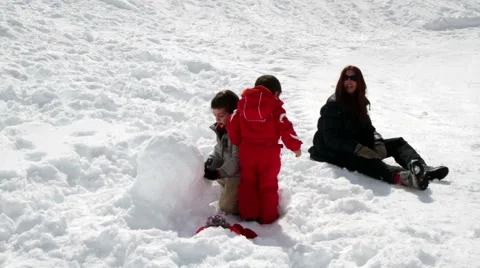 Mum and two children playing with snowballs Stock Footage 61876299