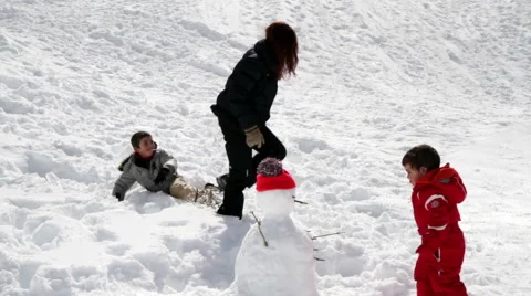 Mum and two children playing with snowballs Stock Footage 61876340
