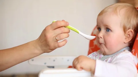 Mum spoon-feeds the baby Stock Footage 80359635