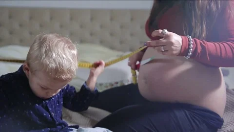 Mummy and her son are measuring a belly. FULL HD slow motion Stock Footage 73977065