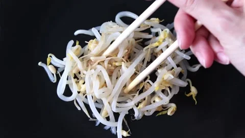 Mung bean sprouts on a black plate. woman takes the sprouts with chopsticks. Stock Footage 209485429