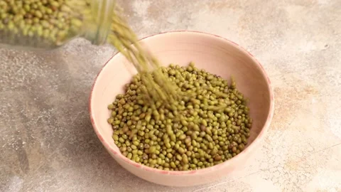 Mung beans pour into a ceramic bowl on a brown concrete Stock Footage 221548681