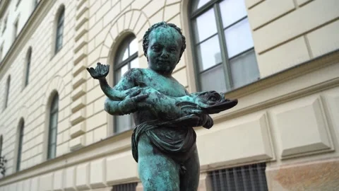MUNICH, GERMANY: Bronze cherub statue with fish sculpture (June, 2025) Stock Footage 343853884