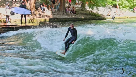 Munich, Germany - Jun 27, 2022: Surfer in the city river called Eisbach Stock Footage 206331529