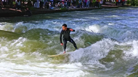 Munich, Germany - Jun 27, 2022: Surfer in the city river called Eisbach Stock Footage 206340100