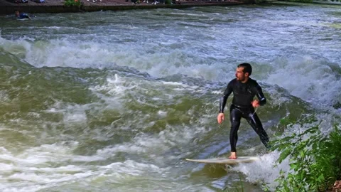 Munich, Germany - Jun 27, 2022: Surfer in the city river called Eisbach Stock Footage 206340264