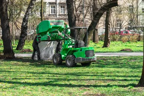 Municipal workers empty the container of the cleaning machine from the leaves Stock Photos