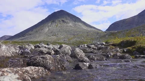 A murmur of a cold stream flowing around the stones at the foot of the mountains Stock Footage 164373003
