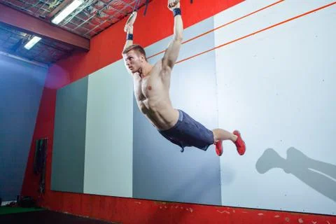 Muscle-up exercise young man doing intense cross fit workout at the gym on Stock Photos