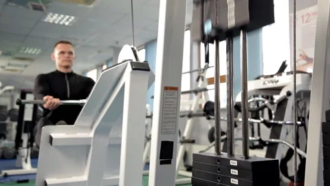 The muscles of the back. Men train on the rowing machine in the gym. A man Stock Footage 106732747