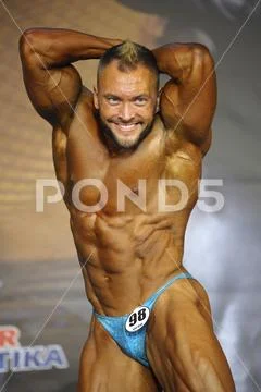 Muscly athlete posing on podium Stock Photos