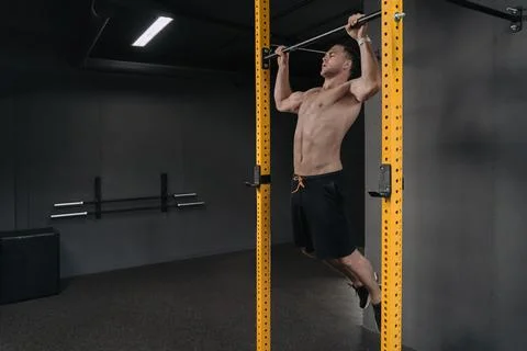 Muscular athlete doing pull ups at crossfit gym Stock Photos