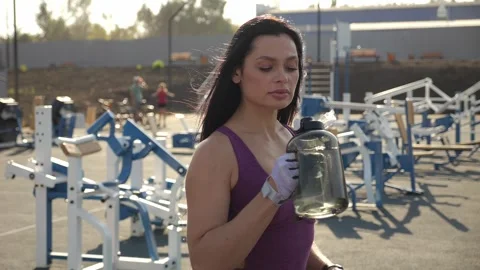 A muscular athlete drinks water during a workout on an outdoor sports ground. Stock Footage 287585357