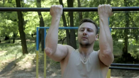 Muscular athlete training biceps pullups on a horizontal bar in the fresh air Stock Footage 130268497