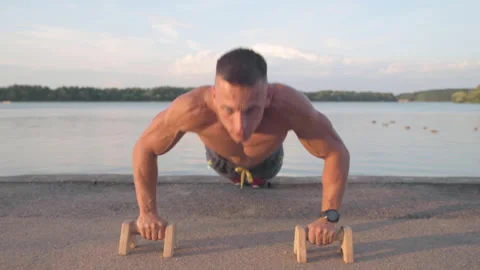 Muscular athletic young man doing pus? ups on the parallettes bar. Sport and  Stock-Footage 159477978