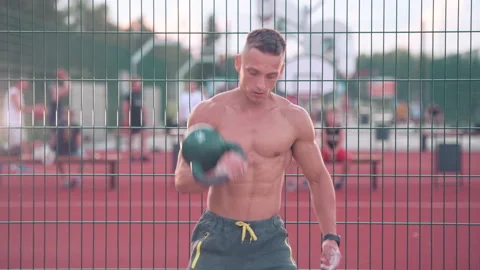 Muscular athletic young man exercise kettlebell lifts above head at the sport 스톡 동영상 159479592
