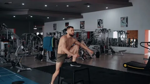 The muscular bearded man performs jumps on an iron chair and then works his feet Video stock 156870870