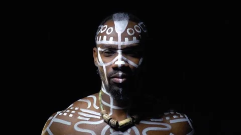 A muscular black man in white patterns on his body depicts a tiger in the dark Stock Footage 82229191