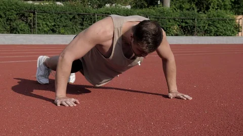 Muscular bodybuilder doing pushups on a race track before running Stock Footage 130168222