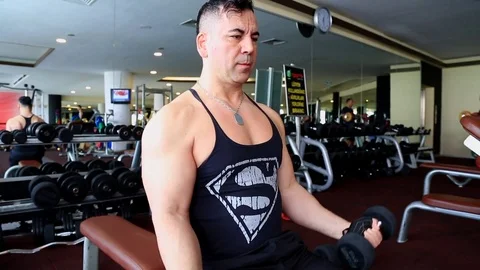 Muscular bodybuilder guy doing exercises with dumbbells in the gym Stock Footage 76059611