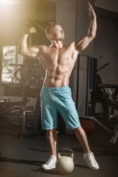Muscular bodybuilder guy doing exercises with weight in gym Stock Photos