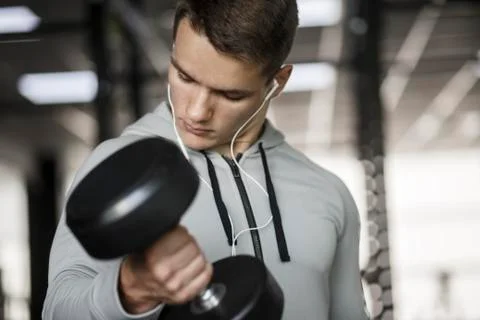 Muscular bodybuilder guy doing exercises with dumbbells in gym Stock Photos