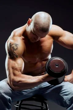 Muscular bodybuilder guy doing exercises with dumbbell Stock Photos