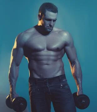 Muscular bodybuilder guy doing exercises with dumbbell over blue background. Stock Photos