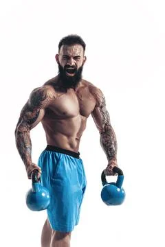 Muscular bodybuilder guy doing exercises with kettlebells over w Stock Photos