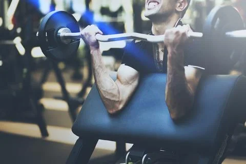 Muscular bodybuilder guy doing exercises with big dumbbell in gym Stock Photos