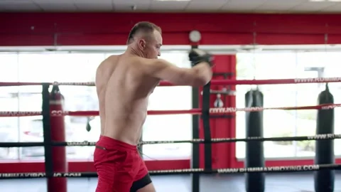 Muscular boxer is practising in the octagon cage. Shadow boxing. Video stock 155638267