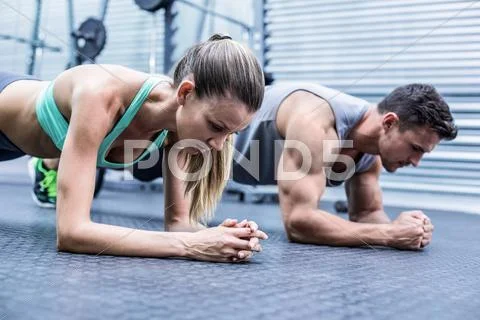 Muscular couple doing planking exercises Stock Photos
