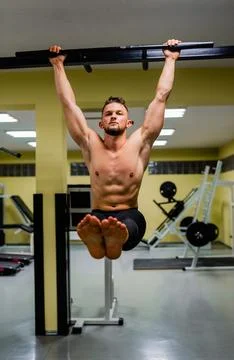 Muscular fit man doing pulling up on horizontal bar at gym. Stock Photos