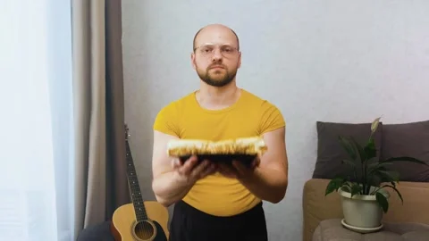 A muscular, funny, nerdy man does a bicep lift with a plate of burritos 스톡 동영상 243758498
